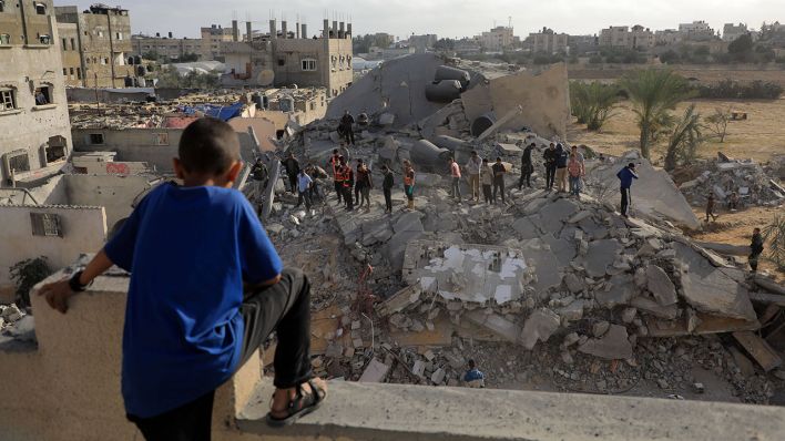 Menschen stehen am 22.04.2024 auf Trümmerteilen zerstörter gebäude in Rafah © imago images/Xinhua